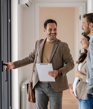 Young married couple talking with a real-estate agent visiting apartment for sale or for rent. Future parents buying an apartment. Real estate concept. A new beginning